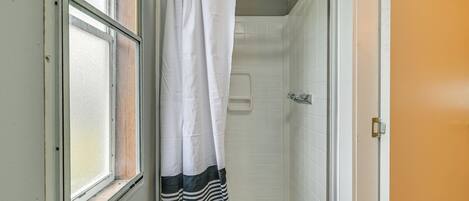 Une salle de bain avec une douche, une fenêtre et une porte.