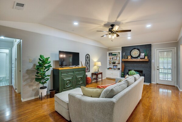 A living room with a sofa, a television, a ceiling fan, and a fireplace. - Home 1 Mi to Historic Gingerbread District & Dtwn! (Waxahachie)