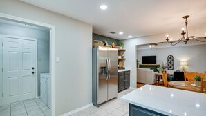 Een moderne keuken met een roestvrijstalen koelkast, een eethoek met een houten tafel en stoelen, en een woonkamer met een bank en een televisie.