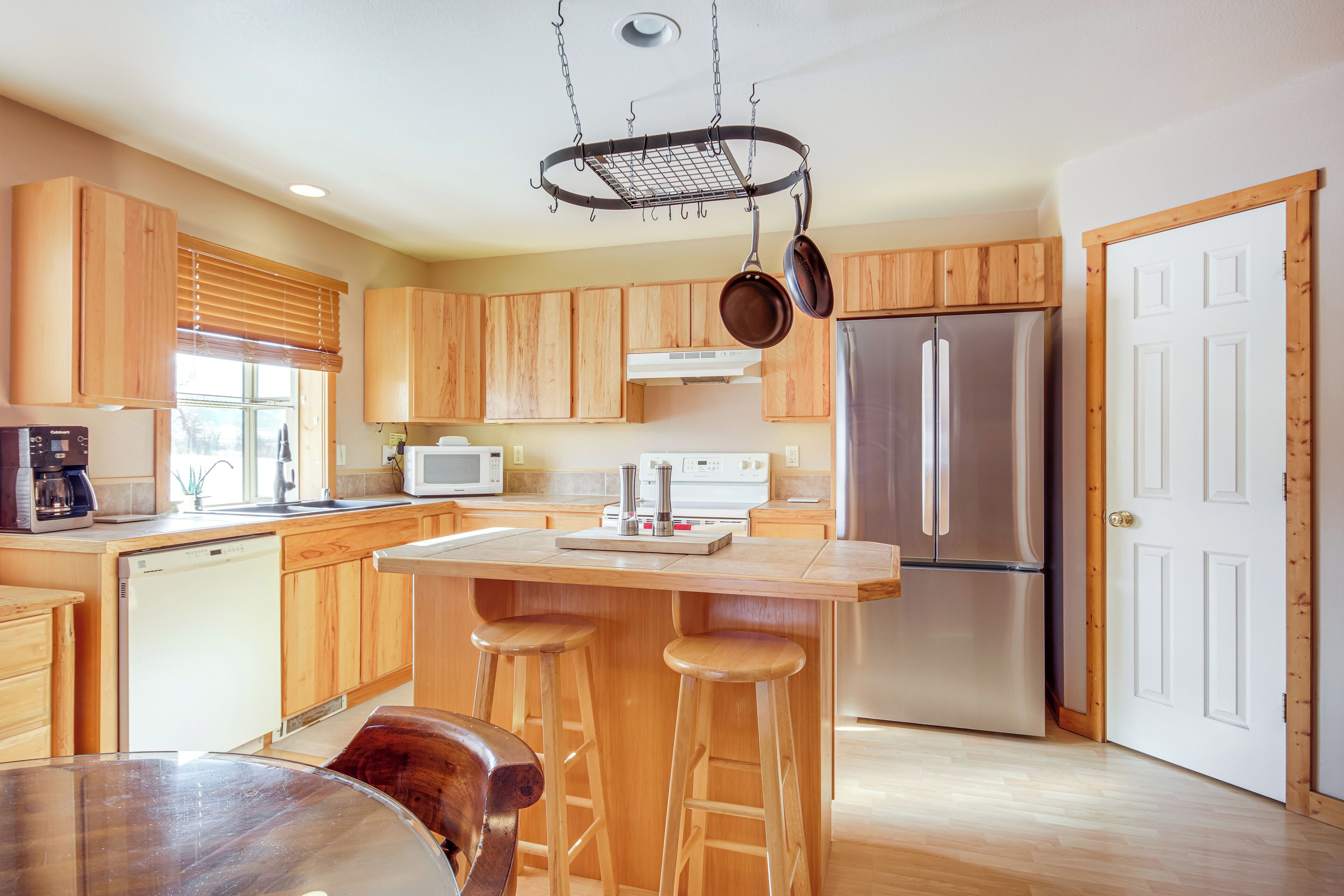 Una cocina moderna con armarios de madera, un refrigerador de acero inoxidable, un microondas y un colgador para ollas.