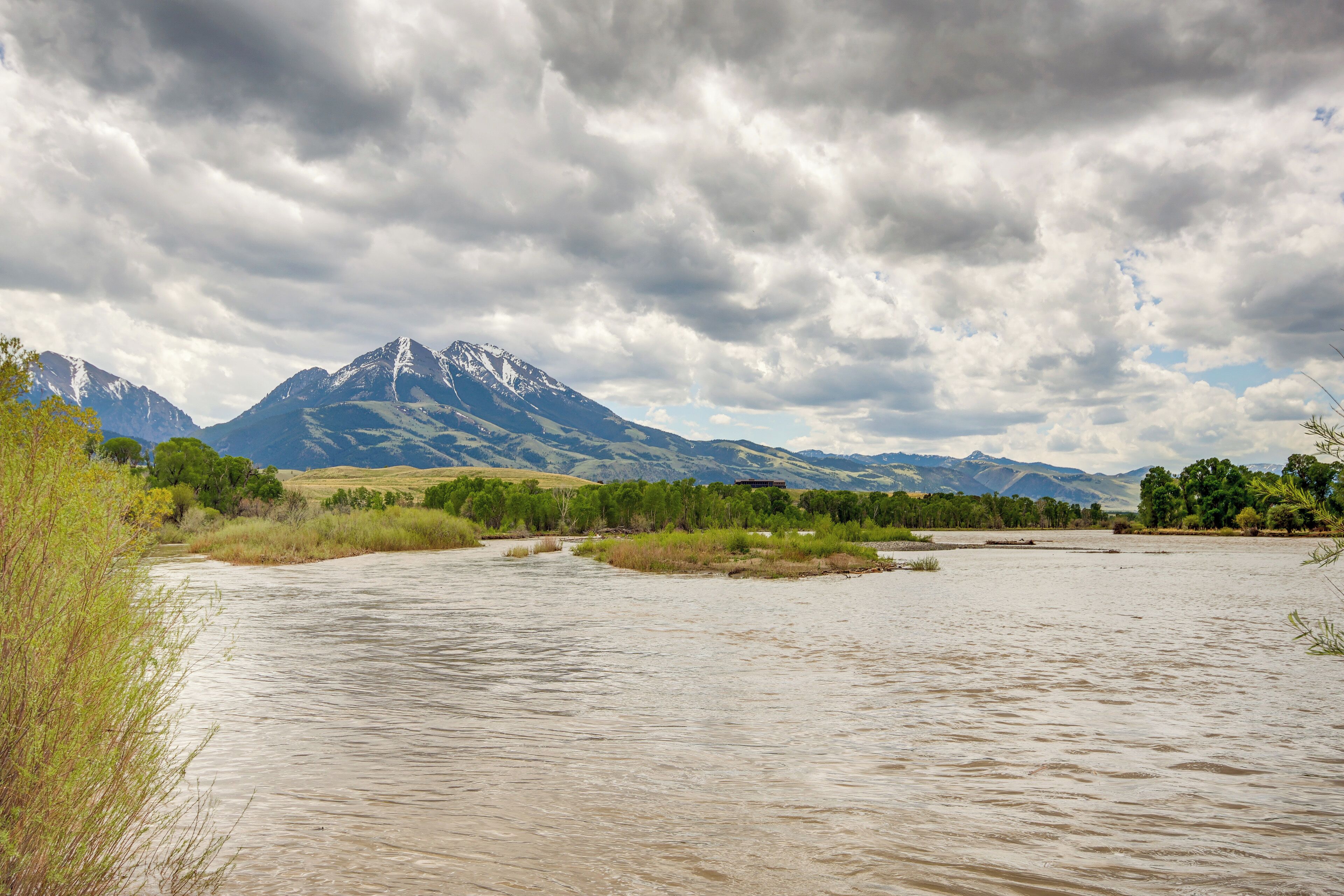 A river with mountains in the background and a cloudy sky.