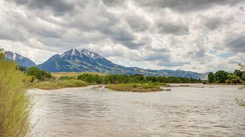 A river with mountains in the background and a cloudy sky.