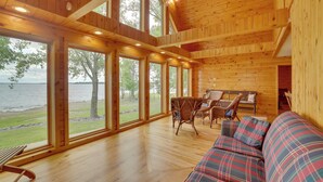 Une cabane en bois dotée de grandes fenêtres, d’un canapé et d’un coin repas.