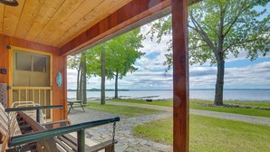 Une cabane en bois avec un porche, un banc et une vue sur un lac.