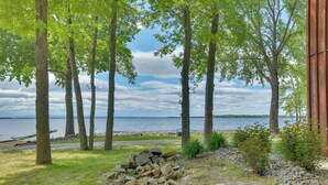 Une propriété située au bord d’un lac, dotée d’un foyer extérieur, d’arbres et offrant une vue sur l’eau.