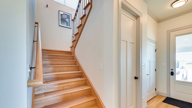 A wooden staircase leading to a white door, a framed picture on the wall, and a window with blinds. - 26-acre Pilot Point Ranch Home w/ Pool & Mini Golf (Pilot Point)