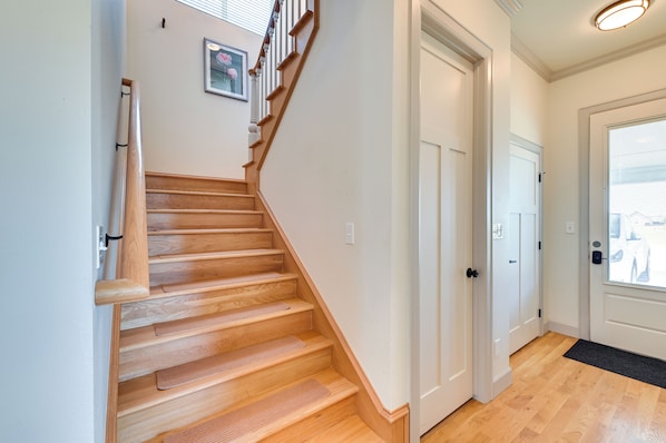 A wooden staircase leading to a white door, a framed picture on the wall, and a window with blinds. - 26-acre Pilot Point Ranch Home w/ Pool & Mini Golf (Pilot Point)