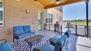 A covered patio with a brick wall, a green door, and a view of a backyard with outdoor furniture. - 26-acre Pilot Point Ranch Home w/ Pool & Mini Golf (Pilot Point)