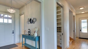 Un couloir agrémenté d’une console de couleur turquoise, d’un lustre et d’un mur décoratif orné de miroirs ronds.