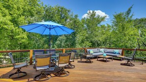 A wooden deck with outdoor furniture, including chairs and a sofa, under a blue umbrella. - Serene Pacific Getaway: Deck, Grill & Fire Pit! (Pacific)