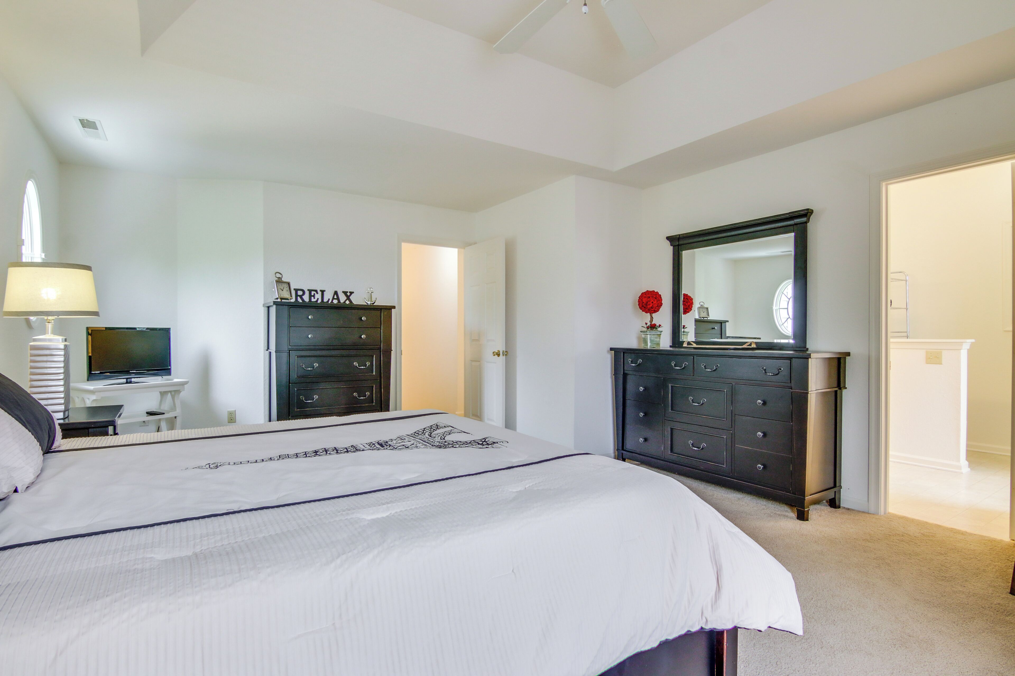 A bedroom with a bed, a dresser, a TV, and a mirror.