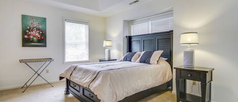 A bedroom with a bed, bedside tables, a ceiling fan, and a painting on the wall.