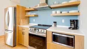 A modern kitchen with stainless steel appliances, wooden cabinets, and built-in shelves for dishes. - Yellowstone Prairie Retreat: 360 Mountain Views! (Emigrant)