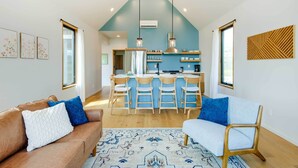 A modern kitchen with a central island, wooden chairs, and a hanging light fixture. - Yellowstone Prairie Retreat: 360 Mountain Views! (Emigrant)
