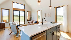 A modern kitchen with a large island, ample natural light, and a view of the outdoors. - Yellowstone Prairie Retreat: 360 Mountain Views! (Emigrant)