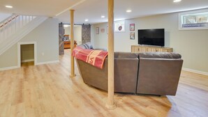 A spacious living room with a brown sectional sofa, wooden columns, a staircase, and a flat-screen TV on the wall. - Family-friendly Blacksburg Retreat w/ Playground! (Blacksburg)