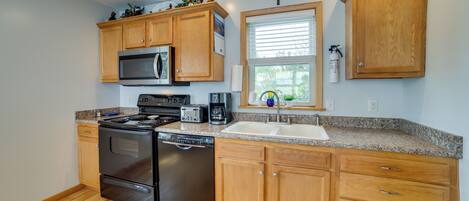 A kitchen with wooden cabinets, a microwave, stove, dishwasher, and granite countertops.