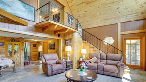 A spacious living room with a large brown leather sofa, a round coffee table, and a staircase leading to an upper level. - Sunny Cedaredge Home w/ Mtn Views - Hike & Fish! (Cedaredge)
