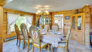 A wooden interior with a dining table set for four, surrounded by ornate chairs, a chandelier, and wooden cabinets. - Sunny Cedaredge Home w/ Mtn Views - Hike & Fish! (Cedaredge)