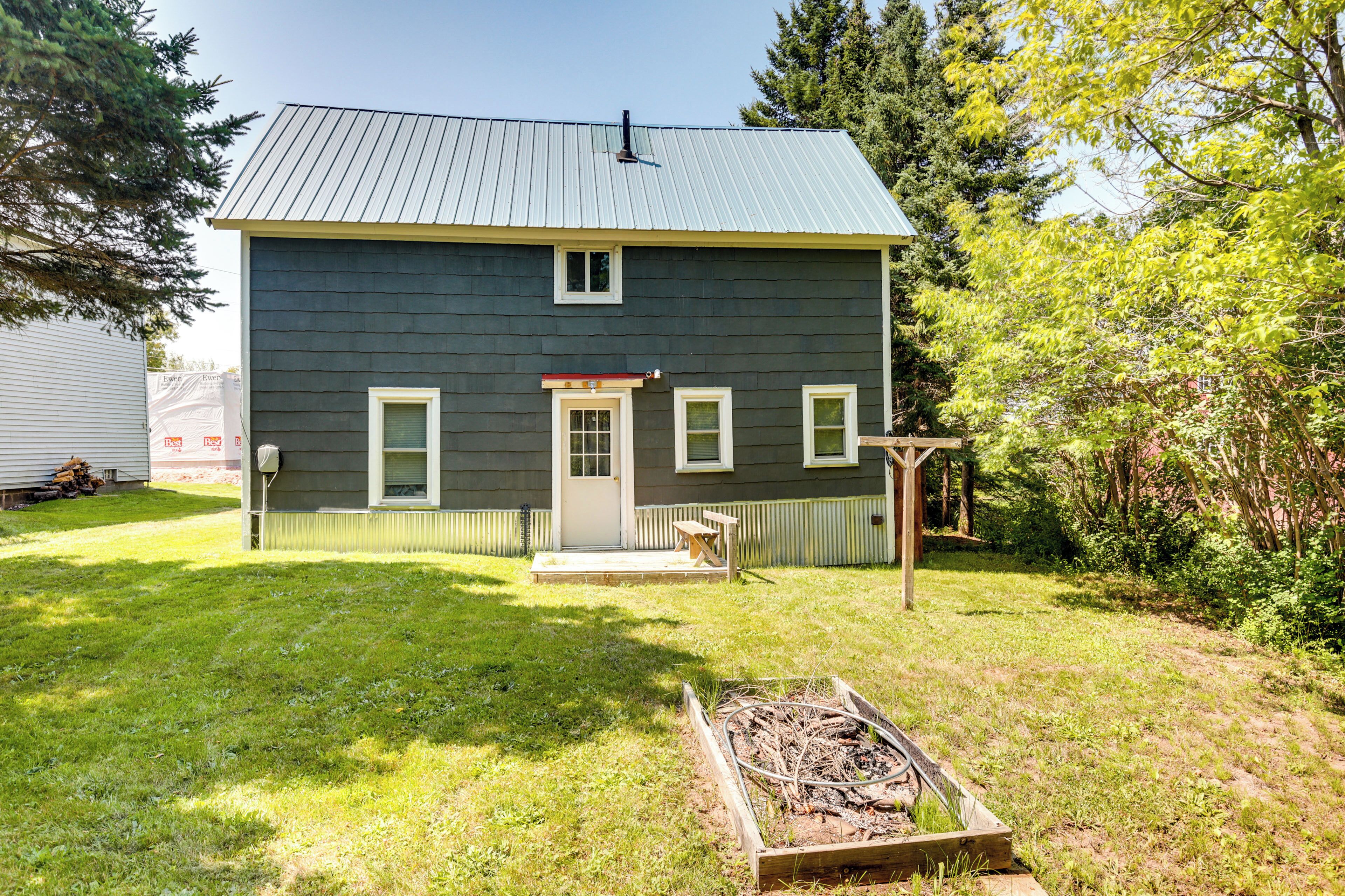 Une maison à deux étages, à l’extérieur sombre, dotée d’un porche et d’un petit jardin.