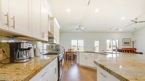 Una cocina moderna con encimeras de granito, armarios blancos y electrodomésticos de acero inoxidable.