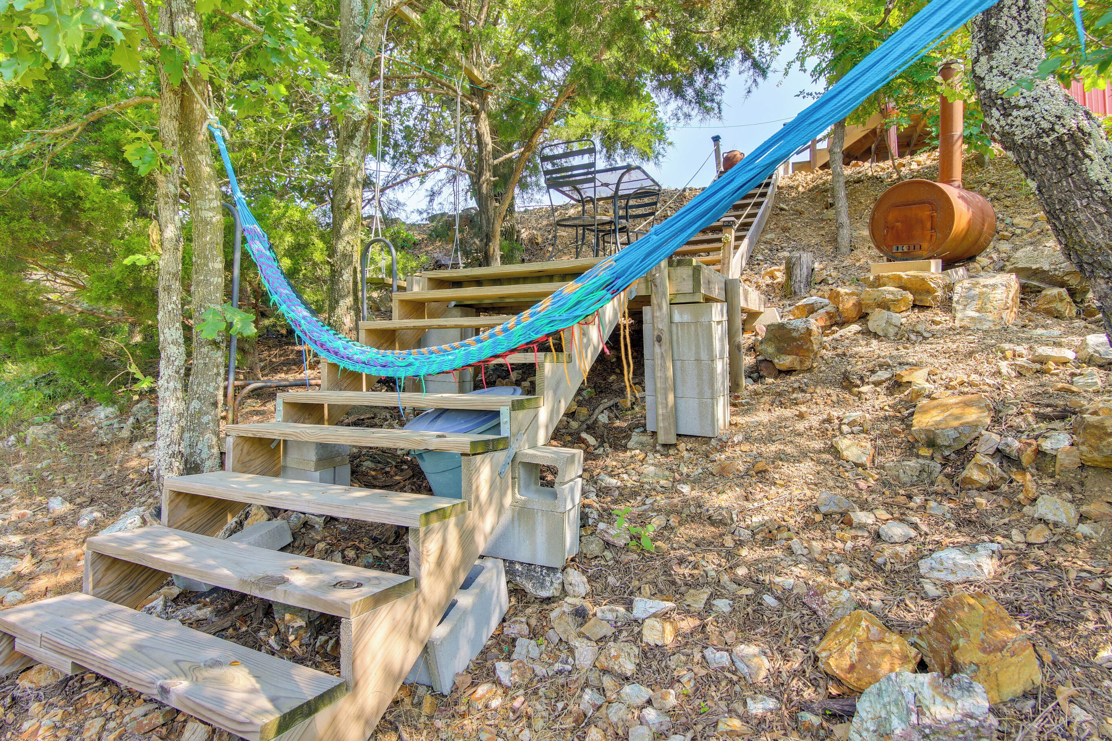 Un escalier en bois avec un hamac, entouré d’arbres et de rochers.