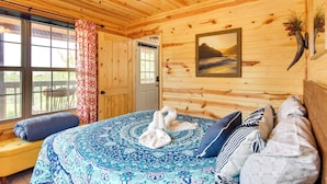 Une pièce de style cabane en bois, avec un lit, un banc et une grande fenêtre.