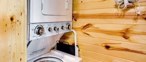 Lavadora y secadora de pared compactas y blancas, con varios mandos y un cable de alimentación visible.