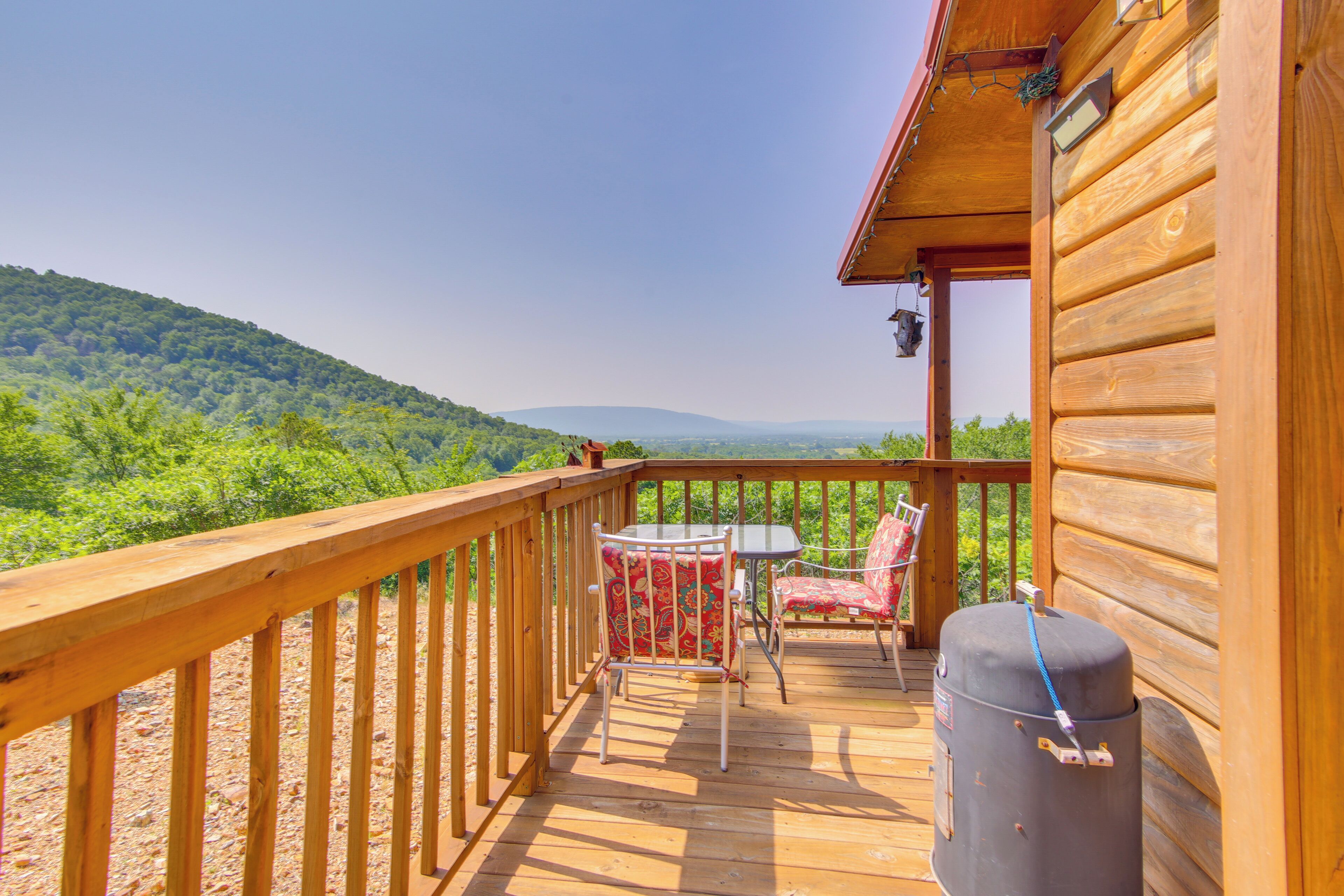 Une terrasse en bois avec une table et des chaises, donnant sur une colline boisée.