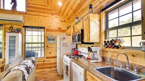 L’intérieur d’une cabane en bois comprend une cuisine, un coin repas et une grande fenêtre.