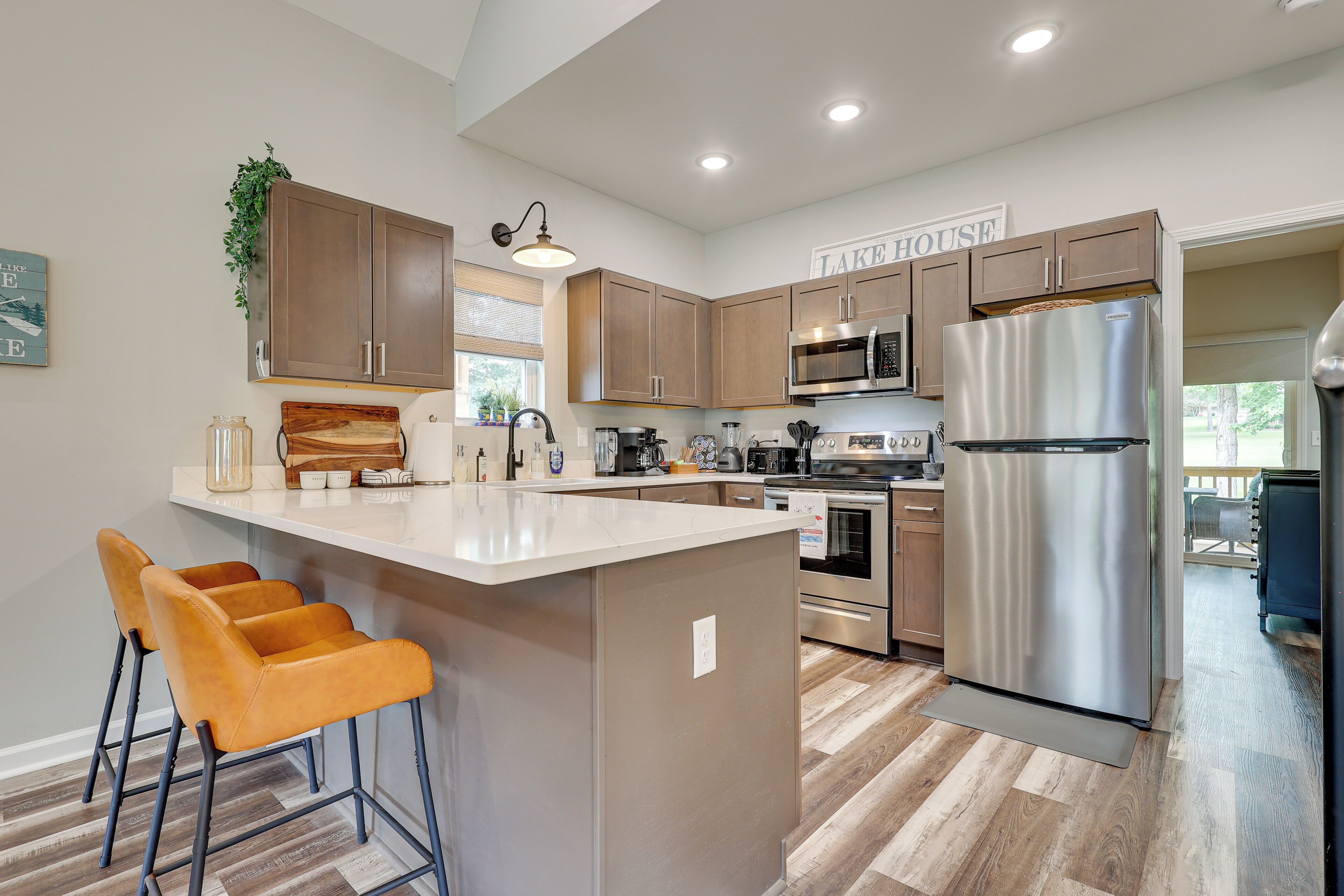 A modern kitchen with wooden cabinets, stainless steel appliances, and a central island with bar stools.