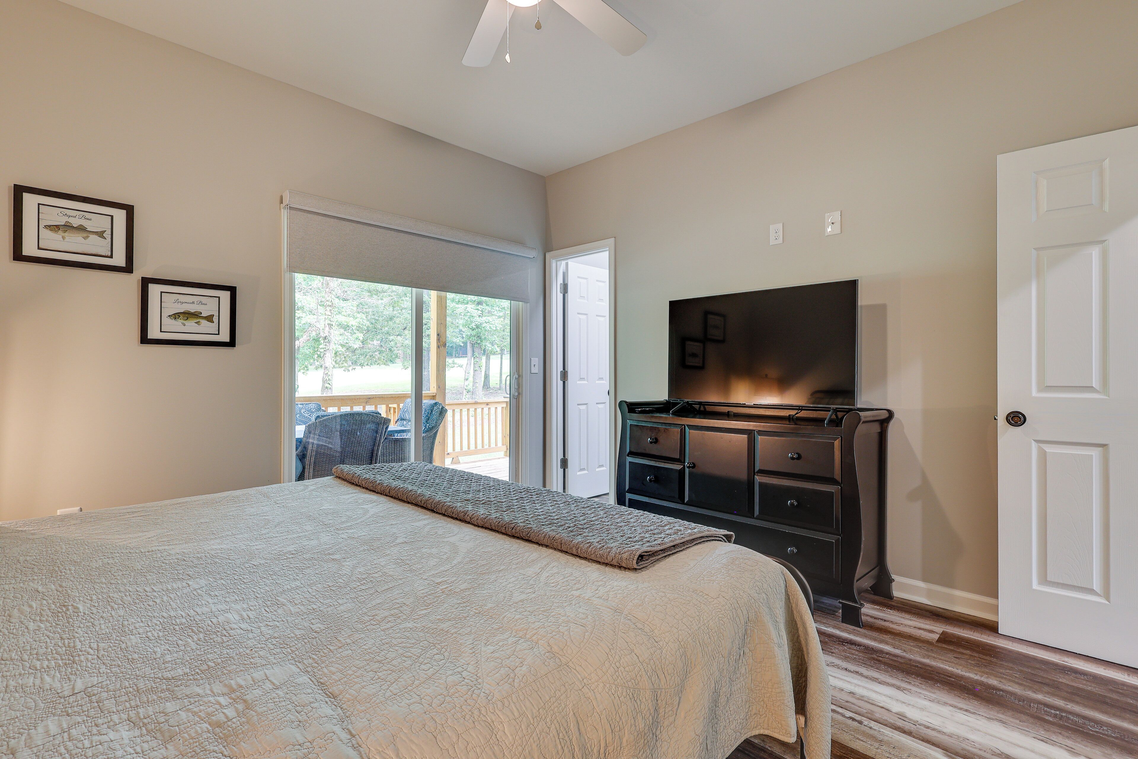 A bedroom with a bed, a dresser, a television, and a door.
