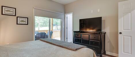 A bedroom with a bed, a dresser, a television, and a door.