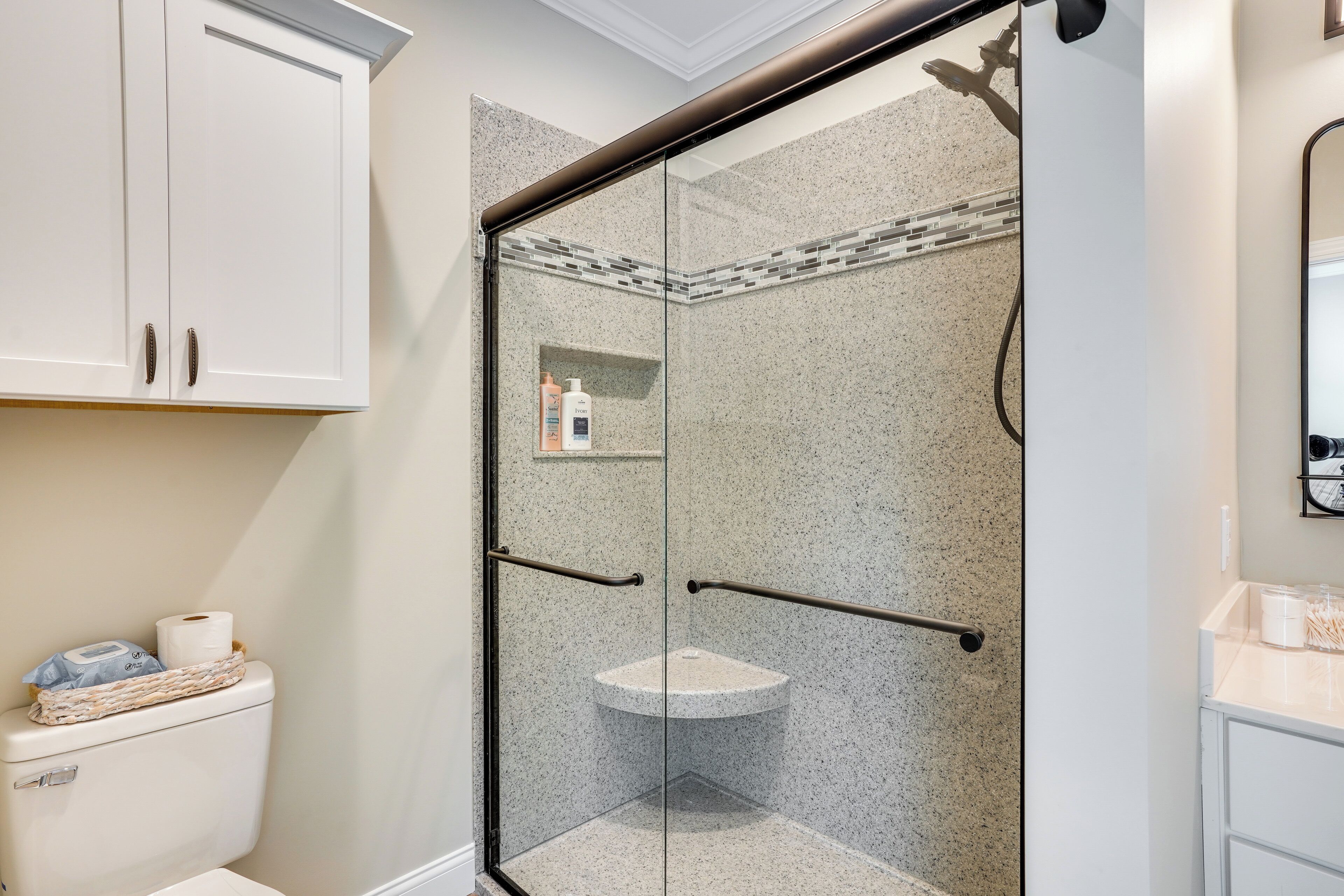 A bathroom with a glass-enclosed shower, a toilet, and a sink.