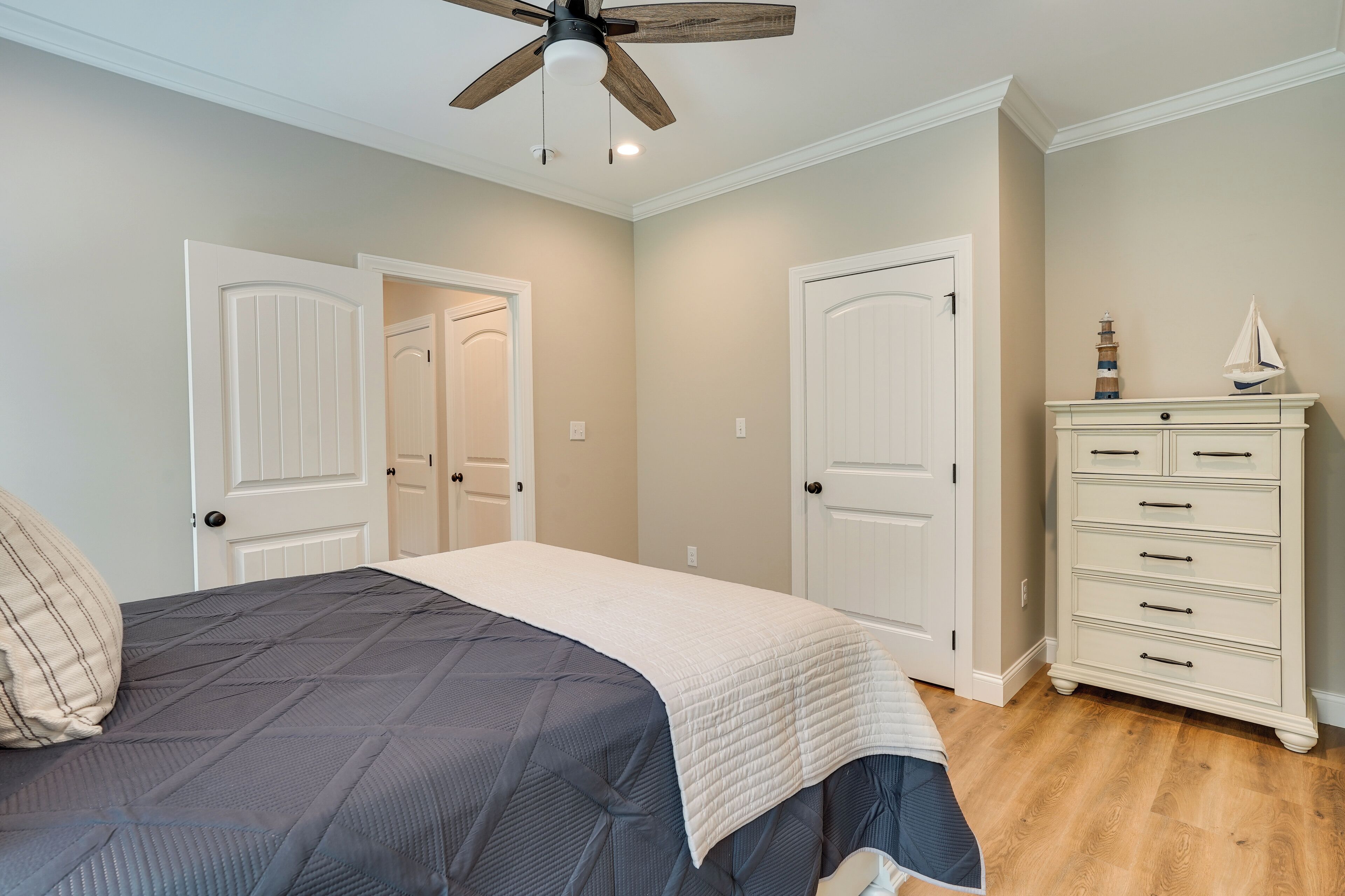 A bedroom with a bed, a dresser, and two doors.