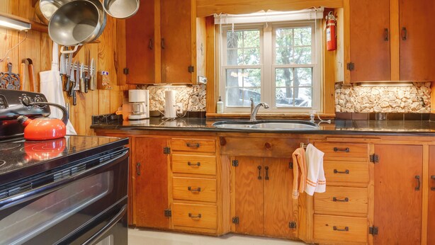 Una cocina con armarios de madera, una estufa y un ventanal con vistas a árboles.