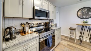 Una cocina moderna con armarios blancos, electrodomésticos de acero inoxidable y un reloj de pared.