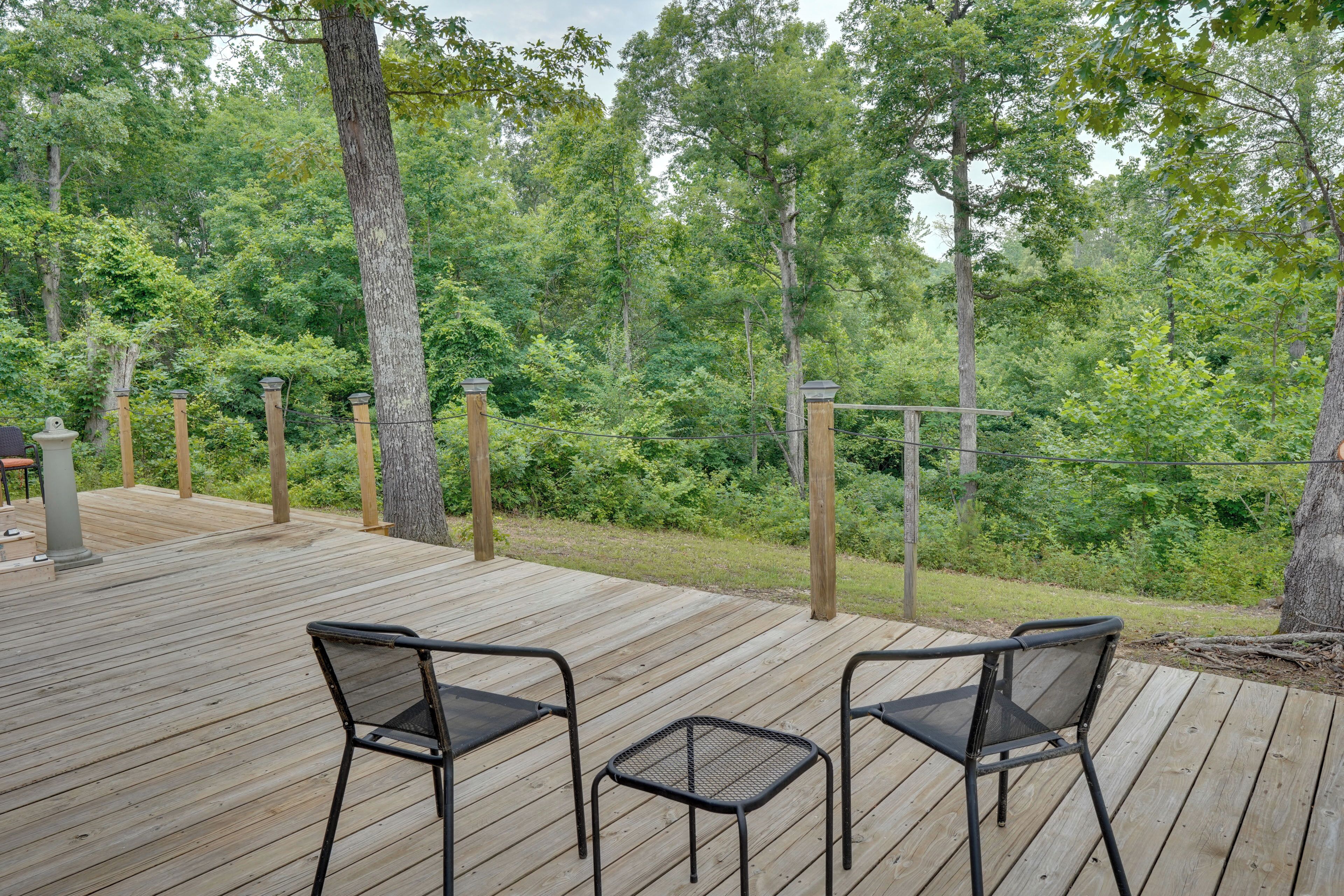 Eine Holzterrasse mit zwei Stühlen und einem kleinen Tisch, umgeben von üppigem Grün.