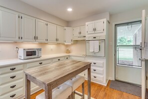 A kitchen with white cabinets, a wooden table, and a microwave.