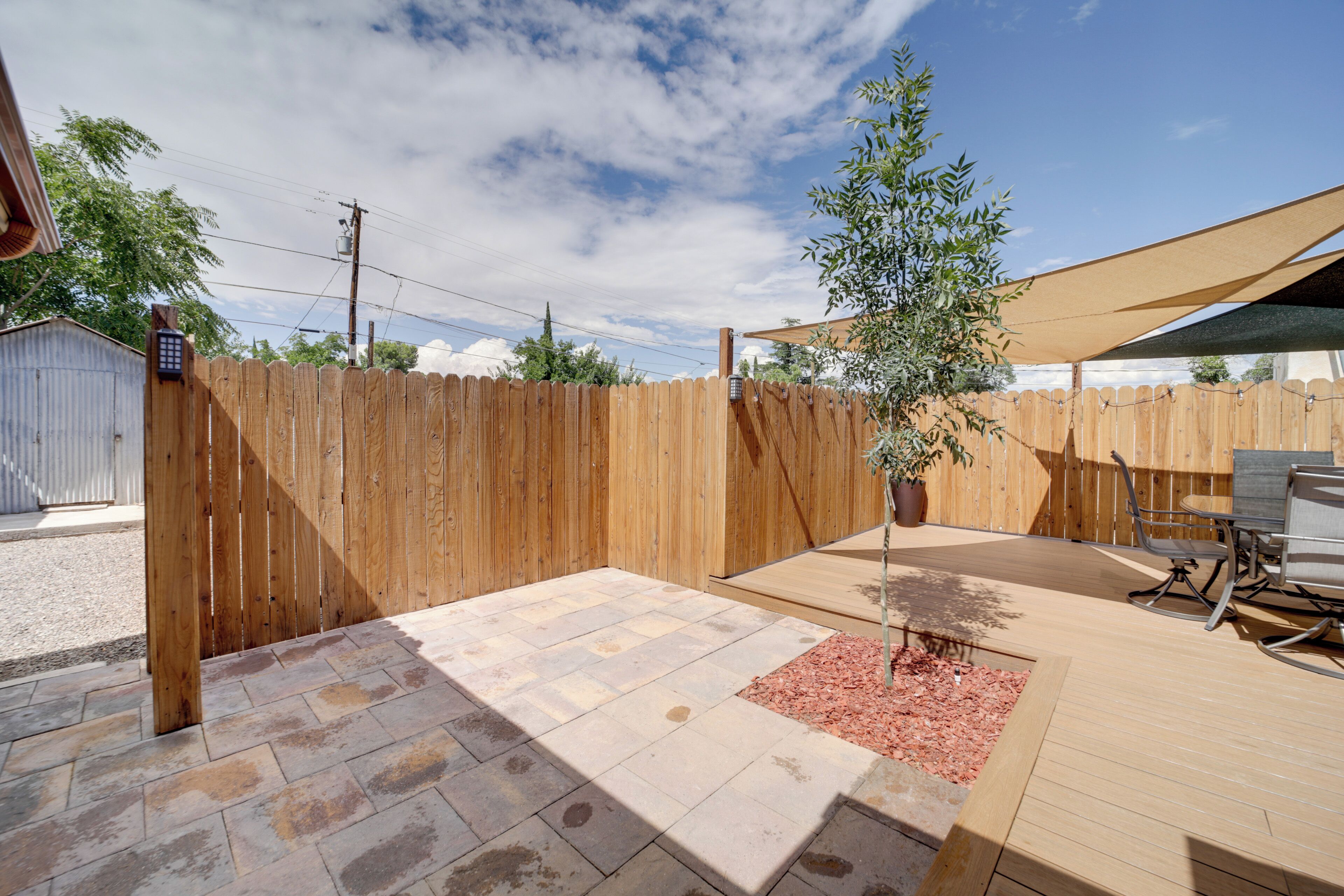 A patio with a wooden fence, a potted plant, and outdoor furniture.