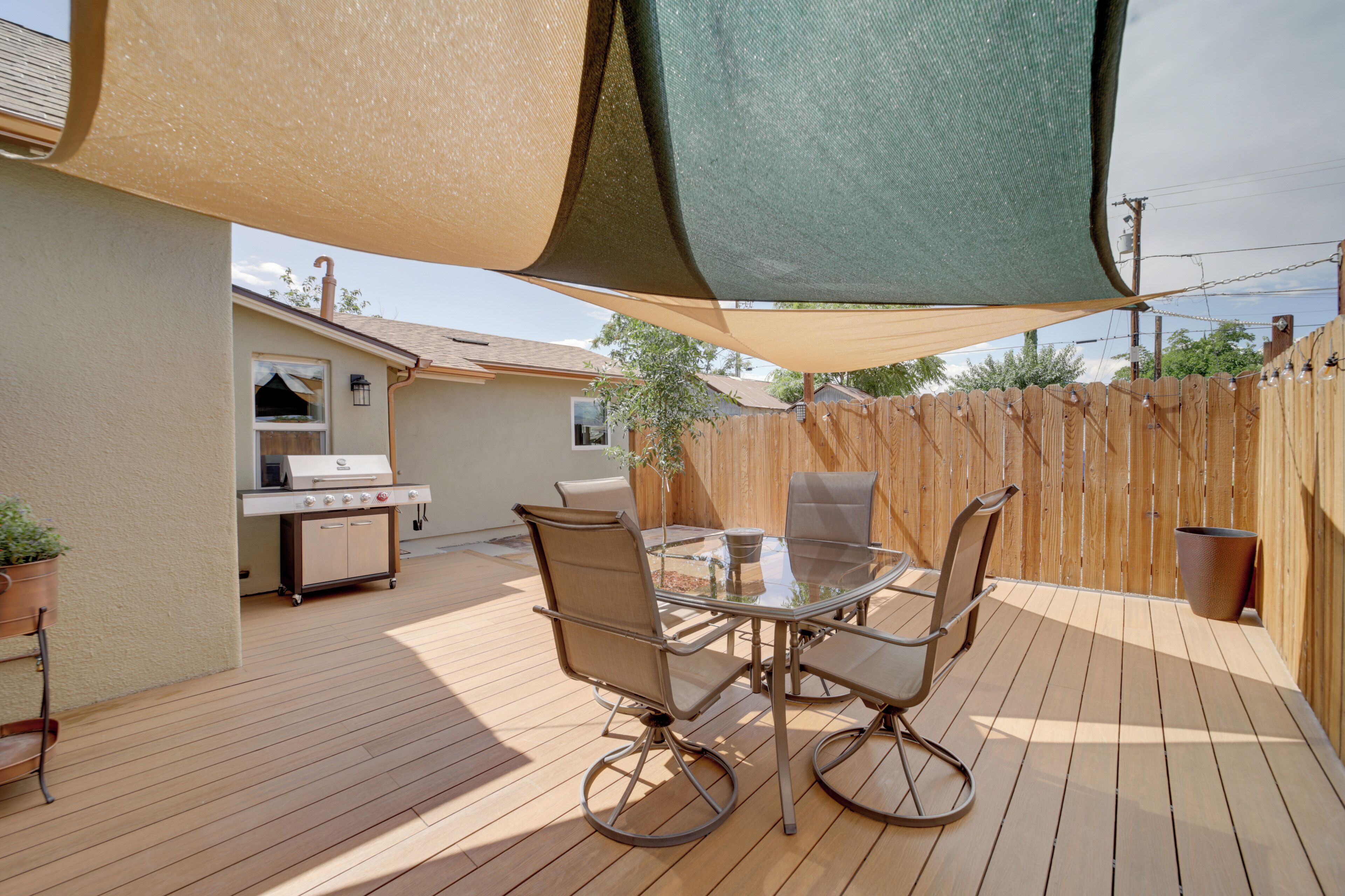 A patio with a table and chairs, a grill, and a wooden deck.