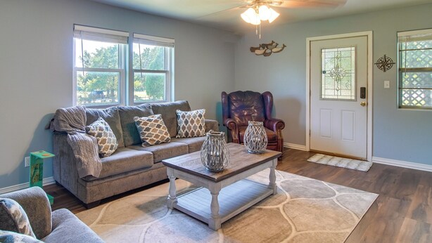 A living room with a sectional sofa, a leather armchair, a coffee table, and a patterned rug. - Cookson Vacation Rental w/ Spacious Yard & Porch! (Cookson)