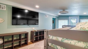A bedroom with a bed, a TV mounted on the wall, a wooden console table, and a window with curtains. - Cookson Vacation Rental w/ Spacious Yard & Porch! (Cookson)