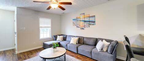 A living room with a sectional sofa, a coffee table, and a ceiling fan.