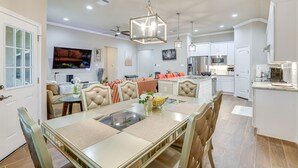 A spacious dining area with a large table, comfortable seating, and a modern kitchen in the background.