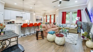 A spacious living area with a kitchen, dining area, and seating with red chairs.