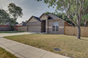 A single-story house with a brick facade, a garage, and a well-maintained lawn.