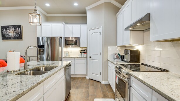 A modern kitchen with white cabinets, stainless steel appliances, and a granite countertop.
