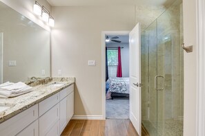 A bathroom with a large mirror, a sink, and a shower area.