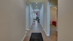 A hallway with a black rug, beige walls, and a ceiling light.